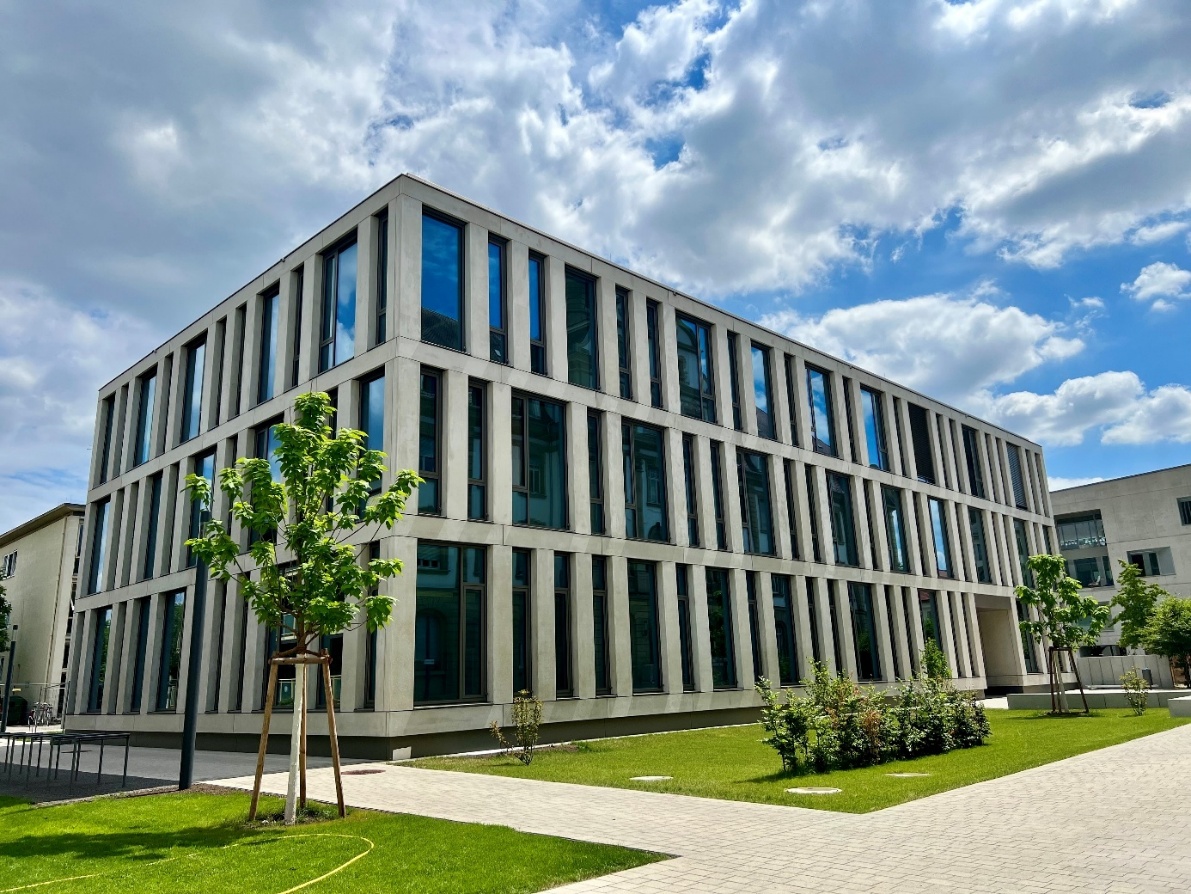 Gesamtansicht des dreigeschossigen InformatiKOM II-Neubaus am KIT mit vorgelagerter Grünfläche aus Rasen und kleinen Bäumen. In diesem Gebäude befindet sich das access@KIT-Institut.